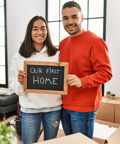 Newcomers to the Triangle showing a sign indicating that this is their first home.